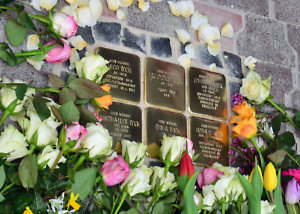 Sechs verlegte Stolpersteine mit Blumen